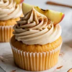Delicious apple cider cupcakes with spiced buttercream frosting on a rustic table.
