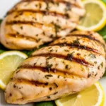 Grilled Lemon Herb Chicken Breasts garnished with herbs on a plate