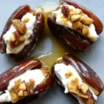 Delicious mascarpone stuffed dates drizzled with maple syrup on a rustic wooden board.