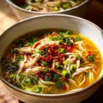 Bowl of Classic Ginger Garlic Chicken Noodle Soup with herbs and noodles