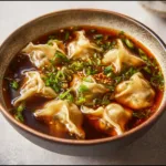 Bowl of homemade potsticker soup with dumplings and herbs