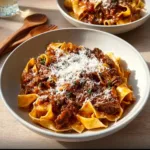 Delicious slow cooker beef ragu served over pasta with fresh herbs and cheese.