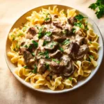 Delicious Beef Stroganoff served with egg noodles and garnished with fresh parsley.