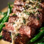 Delicious garlic butter steak served with creamy parmesan sauce on a plate.
