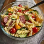 A colorful bowl of high protein Italian pasta salad with vegetables and dressing.