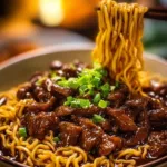 Delicious sticky beef noodles served in a bowl, garnished with herbs.