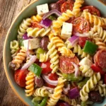 A colorful bowl of classic pasta salad with vegetables and dressing