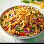 Cold taco pasta salad in a vibrant bowl, garnished with fresh ingredients.