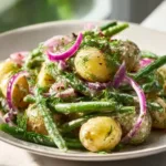 Creamy green bean potato salad served in a bowl with fresh herbs