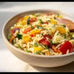 Orzo salad with vegetables and dressing in a bowl