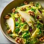 Shaved Brussels and Pear Salad with fresh greens, sliced pears, and dressing