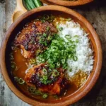 Delicious caramelised soy chicken served on a plate with fresh herbs