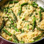 Orzo pasta dish with asparagus garnished with herbs