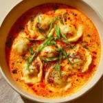 Bowl of simple coconut curry soup with dumplings garnished with herbs